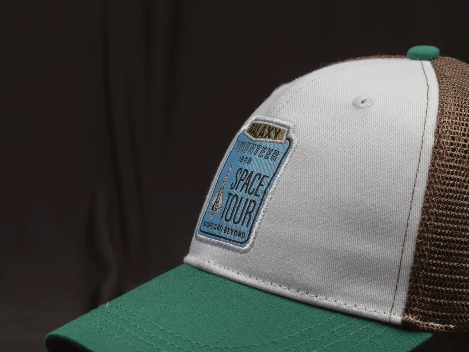 Trucker cap with a finely woven patch on the front panel, photographed on a dark backdrop